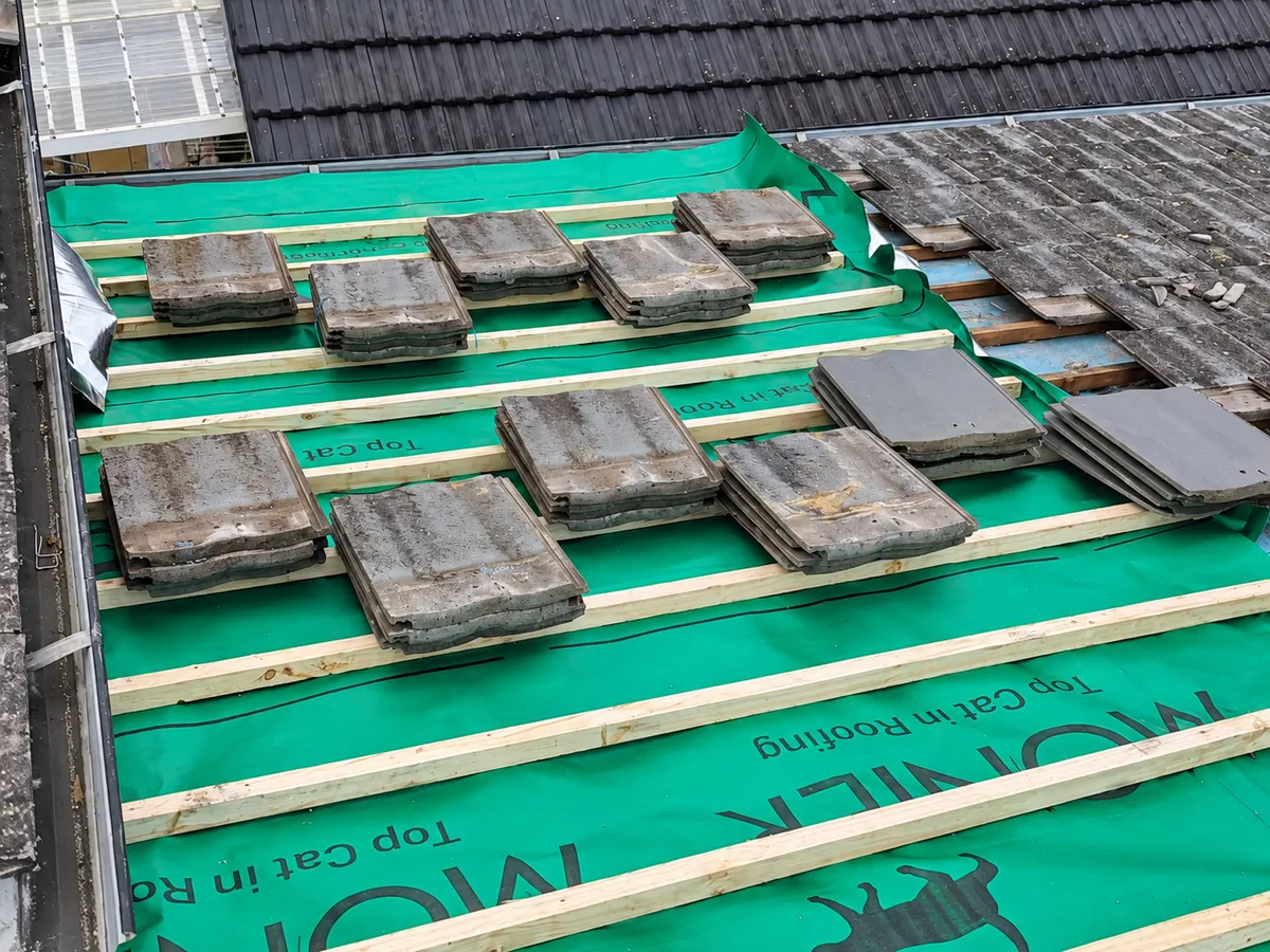 Existing roof tiles stacked on the new battens, ready to be re-laid over the new sarking