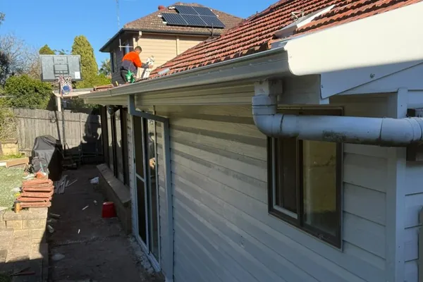 Roofer fitting a new gutter and fascia along a roof edge