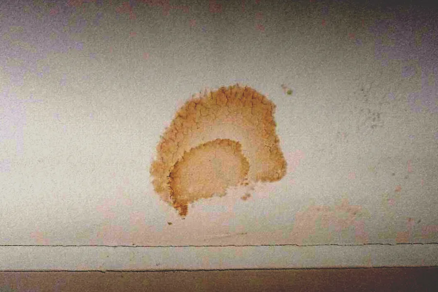 Water stain on a bedroom ceiling from a roof leak