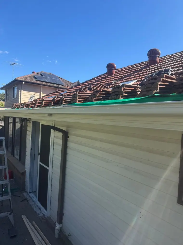 Tile roof mid repair with sections stripped back to the battens, seen from the ground