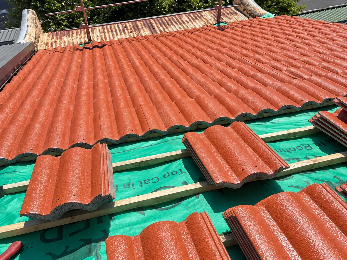 Concrete roof tiles being laid back over new sarking and timber battens on a Sydney roof